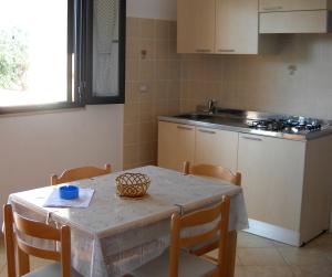 eine Küche mit einem Tisch und Stühlen sowie einem Tisch und einem Tisch und einer Küche in der Unterkunft Zagare Residence in Rodi Garganico