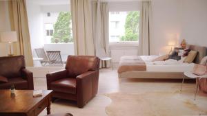 a woman sitting on a bed in a living room at Appartement im Zentrum von Langenhagen mit NETFLIX und Tiefgarage in Hannover