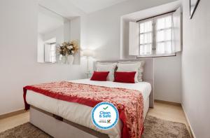 een witte slaapkamer met een groot bed met rode kussens bij Casa Becco dos Assucares, com free garagem - Centro Histórico in Évora