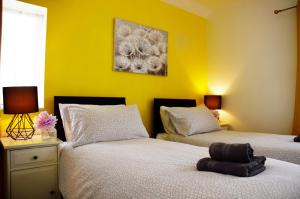 2 letti in una camera con pareti gialle di 1FG Dreams Unlimited Serviced Accommodation- Staines - Heathrow a Stanwell