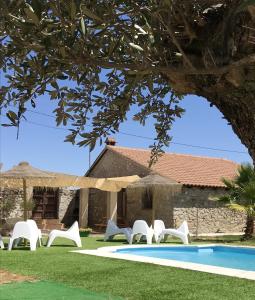 un grupo de sillas y una piscina frente a una casa en 4 bedrooms house with shared pool enclosed garden and wifi at Alcaracejos, en Alcaracejos