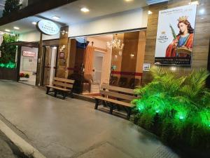 a building with two benches in front of a store at Pousada Santa Catarina in Cachoeira Paulista