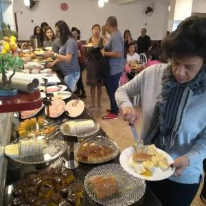 Un groupe de personnes autour d'un buffet de nourriture dans l'établissement Pousada Santa Catarina, à Cachoeira Paulista
