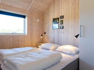 2 Betten in einem Zimmer mit Holzwänden und einem Fenster in der Unterkunft Holiday home Fanø XLIII in Fanø