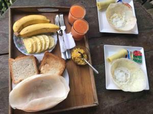 een dienblad met ontbijtproducten met bananen en brood bij Samadhi Nature Resort in Ella