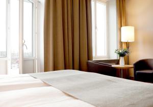 1 dormitorio con 1 cama, 1 silla y ventanas en Grand Hotel Falkenberg en Falkenberg