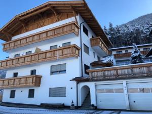 a white house with wooden balconies and a garage at Forchnerhof -Appartement Dolomitenblick in Rodengo