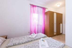 duas camas num quarto com cortinas cor-de-rosa em PAPE PUNAT apartmani i sobe em Punat