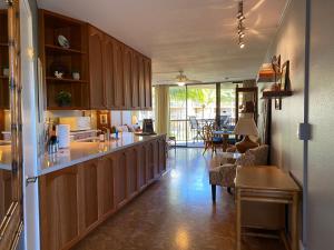 a kitchen with wooden cabinets and a living room at Perfect for families and couples - Maui Sunset A-203 in Kihei