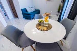 - une table et des chaises blanches avec une bouteille et des fruits dans l'établissement Euroholiday apartments, à Turanj