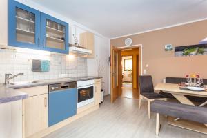 eine Küche und ein Esszimmer mit blauen Schränken und einem Tisch in der Unterkunft Bergheim Komfort Ferienwohnungen in Walchsee