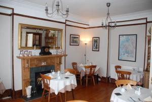 a dining room with tables and a fireplace at Denehurst Guest House - Adults Only in Windermere