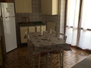 Il comprend une cuisine équipée d'une table et d'un réfrigérateur blanc. dans l'établissement Appartamento Signorile, à Alghero