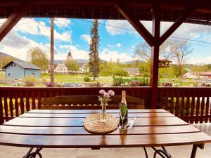 - une table en bois avec une bouteille et des fleurs sur une terrasse couverte dans l'établissement Penzion U Rodinky, à Bělá pod Pradědem