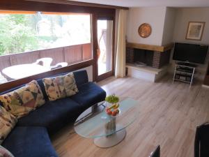 a living room with a blue couch and a glass table at Hof Arosa in Arosa