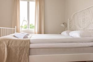 1 dormitorio con 2 camas con sábanas blancas y ventana en Hotel Nestor & Restaurant Back Pocket, en Korpo