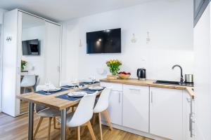 a kitchen and dining room with a table and chairs at Apartament 8B Blue Marine Poddąbie in Poddąbie