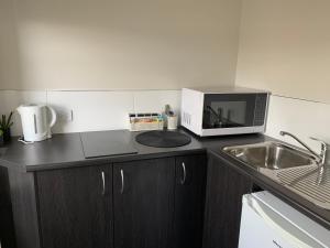 a kitchen with a microwave and a sink at Queens Arms Hotel in Longford