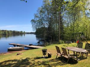 einen Picknicktisch und Stühle am Ufer eines Sees in der Unterkunft Naturskönt boende vid Sjö in Skånes Fagerhult