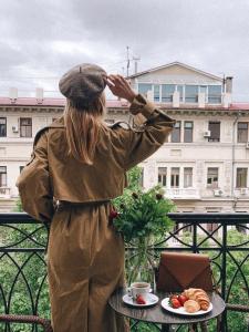 Eine Frau steht auf einem Balkon mit einem Tisch. in der Unterkunft Frapolli Hotel in Odessa