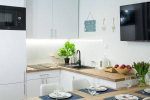 a kitchen with white cabinets and a table with chairs at Apartament 3B Blue Marine Poddąbie in Poddąbie
