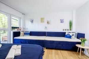 Cette chambre comprend deux lits et un canapé bleu. dans l'établissement Apartament 3B Niebieskie Apartamenty z basenem krytym, odkrytym, salą zabaw, animacjami, à Poddąbie 36 autres photos