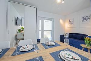 a dining room with a table and a blue couch at Apartament 3B Blue Marine Poddąbie in Poddąbie