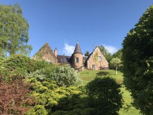 stary dom na zielonym wzgórzu z drzewami w obiekcie Highland Bear Lodge & Luxury Bear Huts w mieście Drumnadrochit