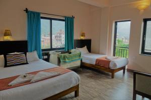 a hotel room with two beds and a balcony at Hotel Karuna in Pokhara