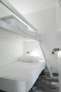 
a bed room with a white bed and a white wall at La Cocotera Boutique Hostel & Coworking in Tarifa
