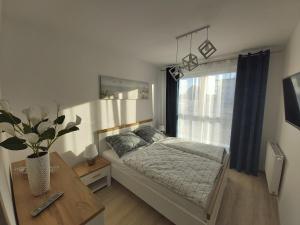 sypialnia z łóżkiem, stołem i oknem w obiekcie Apartament Przy Lesie Słoneczne Tarasy w Dziwnówku