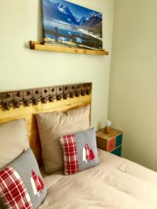 a bed with two pillows and a picture on the wall at Appartement - Terrasse "L' orée des monts" - Loudenvielle location in Loudenvielle