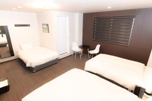 a hotel room with two beds and a table and chairs at Hotel Kojan in Osaka