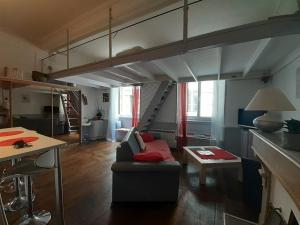 uma sala de estar com um sofá e um loft em coquet studio en mezzanine NUIT pour 2 personnes em Saint-Girons