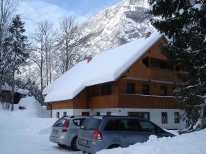 博希尼的住宿－渤興湖公寓，两辆汽车停在一座有雪盖的建筑前