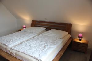 een slaapkamer met een bed met 2 lampen op nachtkastjes bij Ferienhof Frerichs ihr Feriendomizil am Meer in Wangerland