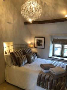 a bedroom with a large white bed with a chandelier at Cottage in the heart of Montacute in Montacute