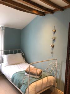 1 dormitorio con cama de metal y pared azul en Cottage in the heart of Montacute, en Montacute