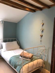 ein Schlafzimmer mit einem Metallbett mit blauer Wand in der Unterkunft Cottage in the heart of Montacute in Montacute
