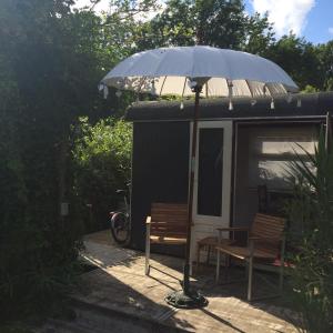 an umbrella and a bench in front of a shed at Gipsy wagon near Amsterdam and beach in Velserbroek 