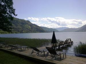 a group of chairs sitting on a dock next to a lake at Appartementhaus Karantanien am Ossiacher See in Ossiach