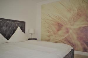 a bedroom with a white bed with a large painting on the wall at Relaxzone 202 - Hohen Wieschendorf in Hohen Wieschendorf