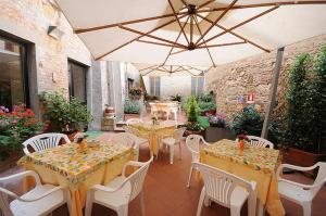 d'une terrasse avec des tables, des chaises et un parasol. dans l'établissement Albergo Duomo, à Montepulciano