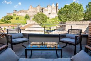 a patio with chairs and a table with a castle in the background at Le Loft de La Tour Pinte in Carcassonne