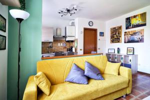 uma sala de estar com um sofá amarelo com almofadas azuis em Casa Zoe Apartment Free parking,self check in & free wi fi em Parma