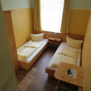 2 Betten in einem kleinen Zimmer mit einem Tisch in der Unterkunft Gasthaus zum Lamm in Ettenheim
