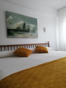 1 cama con 2 almohadas y una pintura en la pared en Hostal Pereiriña, en Cee