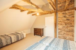 a bedroom with two beds and a brick wall at Gites chez Antonin in Tour-de-Faure