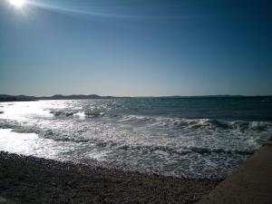 a beach with the sun shining on the water at Apartments Roncevic in Zadar