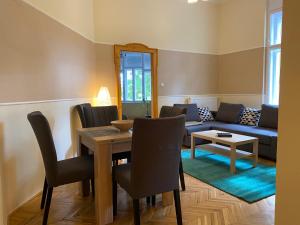 a living room with a table and a blue couch at Ambrózia Apartman in Eger